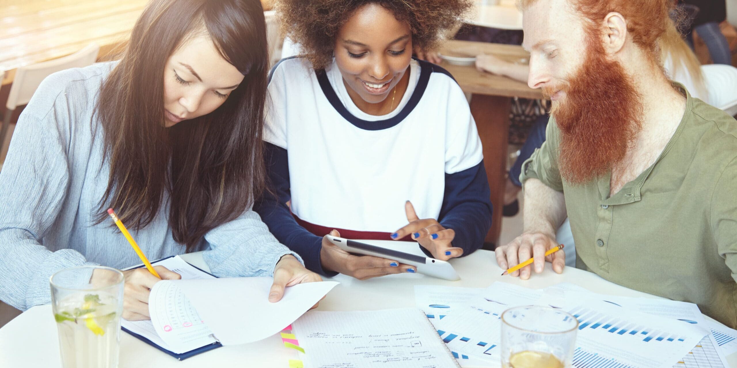 Three young adults reviewing financial documents together at a table